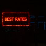 Bild von einem rot leuchtentem Schild mit "Best Rates". Der Hintergrund ist schwarz.