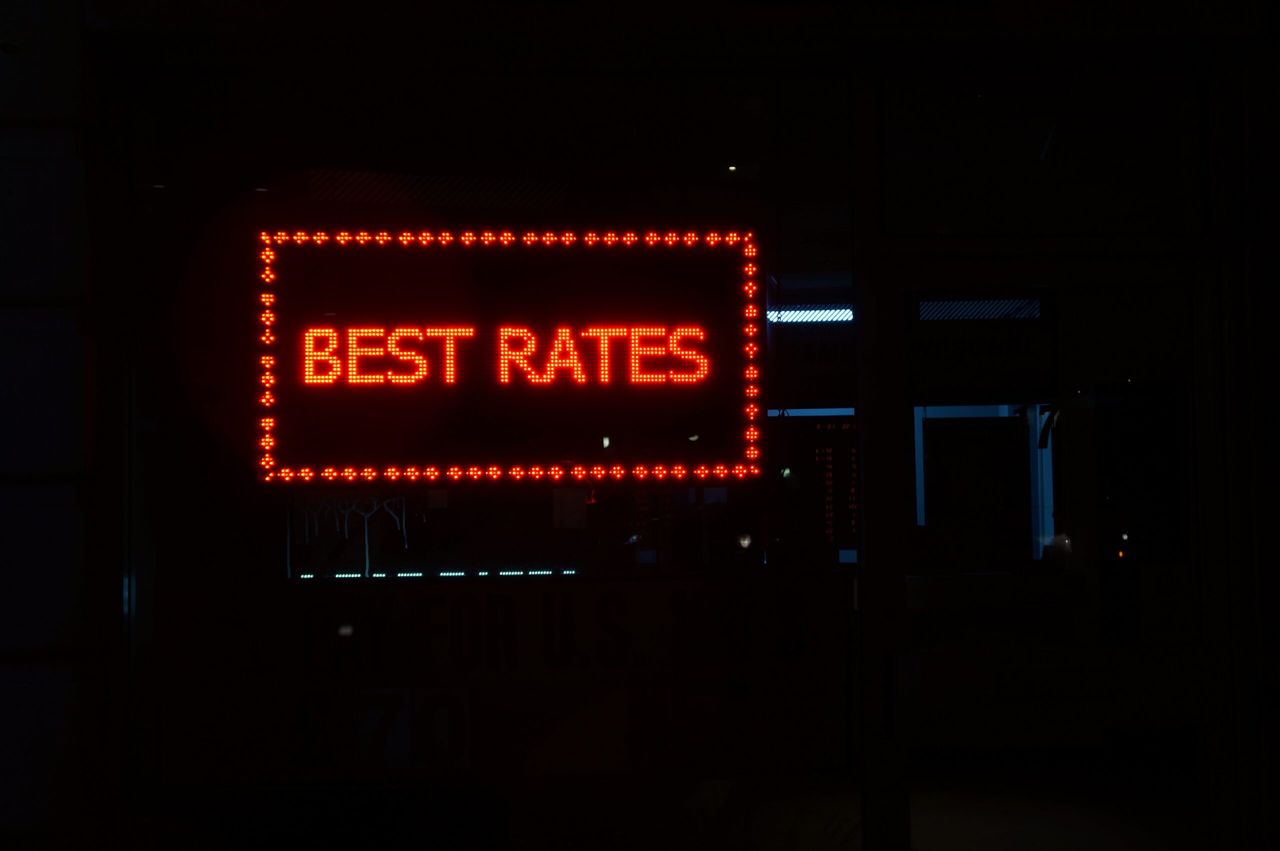 Bild von einem rot leuchtentem Schild mit "Best Rates". Der Hintergrund ist schwarz.